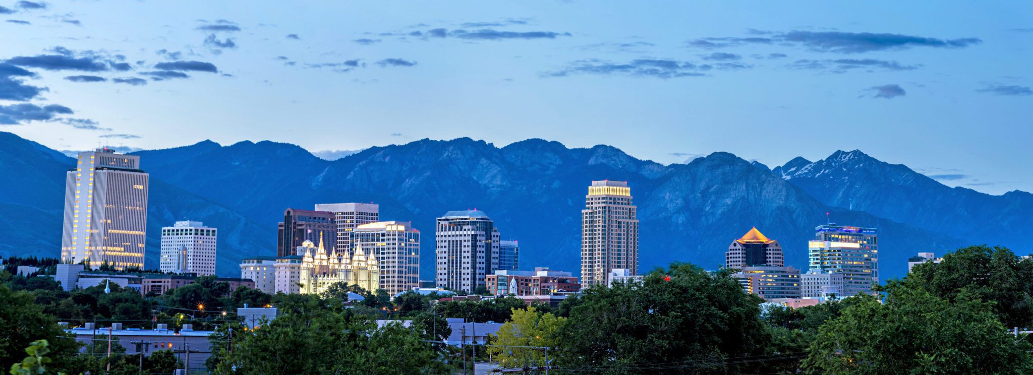 City skyline with mountain backdrop at dusk.